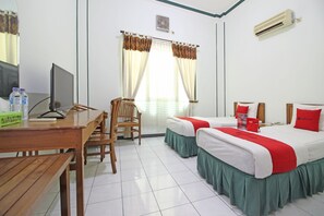 Habitación de hotel con dos camas, un escritorio, una silla y una ventana con cortinas.