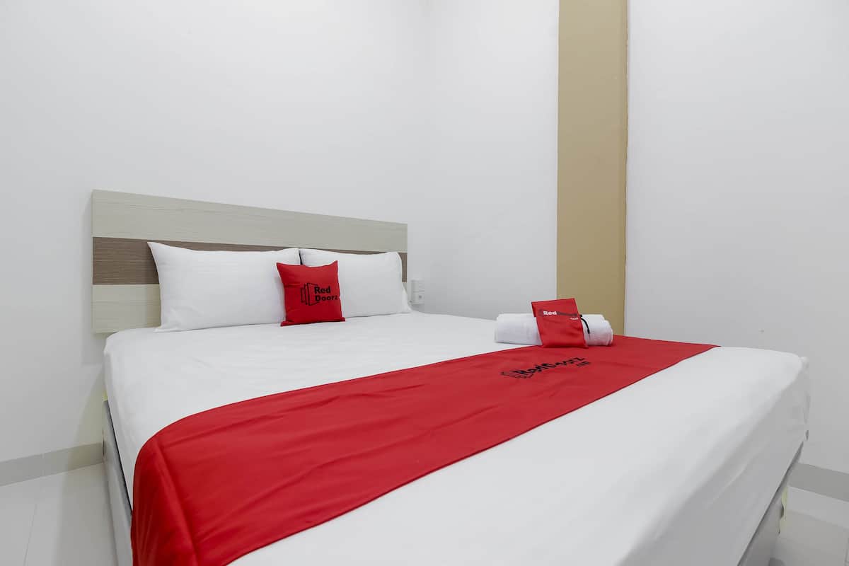 Ein Hotelzimmer mit einem Bett, weißer Bettwäsche, einer roten Tagesdecke und roten Kissen.