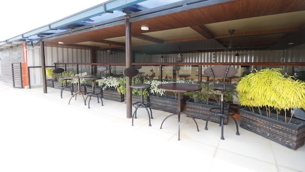 An outdoor seating area with tables and chairs, surrounded by potted plants. - RedDoorz Plus near DC Mall Batam (Batam)