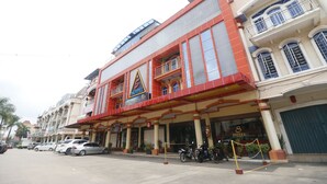 A hotel with a prominent 'S HOTEL' sign, multiple balconies, and a parking area with several cars and motorcycles. - RedDoorz Plus near DC Mall Batam (Batam)