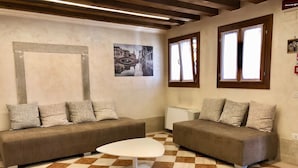Ein Wohnzimmer mit zwei Sofas, einem Couchtisch, einem Schachbrettfußboden und einem Gemälde einer Brücke.