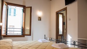 Ein Hotelzimmer mit Bett, Fenster, Spiegel und Nachttisch.