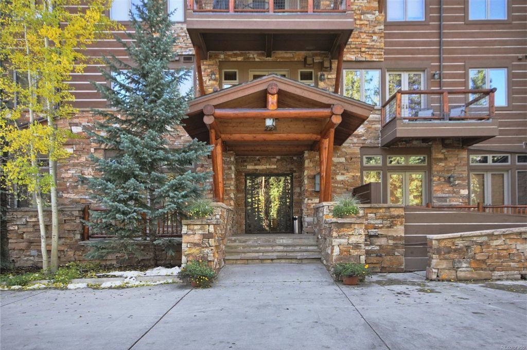 A multi-story building with a stone facade, a wooden porch, and a staircase leading to the entrance.