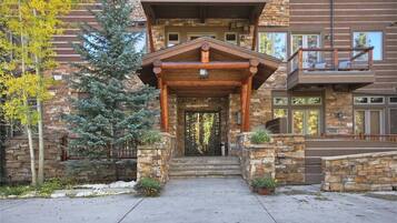 A multi-story building with a stone facade, a wooden porch, and a staircase leading to the entrance.