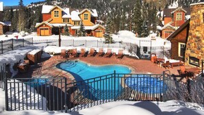 Un complexe hôtelier doté d’une piscine entourée de chaises longues, d’un bâtiment en pierre et offrant une vue sur un paysage montagneux.