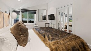 A modern bedroom with a large bed, a television, and a view of the outdoors through a window. - Downtown Aspen Vacation Rentals (Aspen)