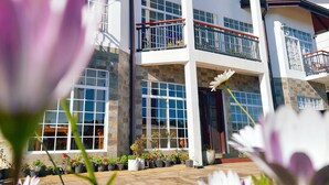 A multi-story building with large windows, balconies, and a covered entrance area. - Misthill Rest (Nuwara Eliya)