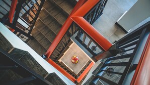 A high-angle view of a staircase with red railings and a central area with a round table and chairs. - Misthill Rest (Nuwara Eliya)