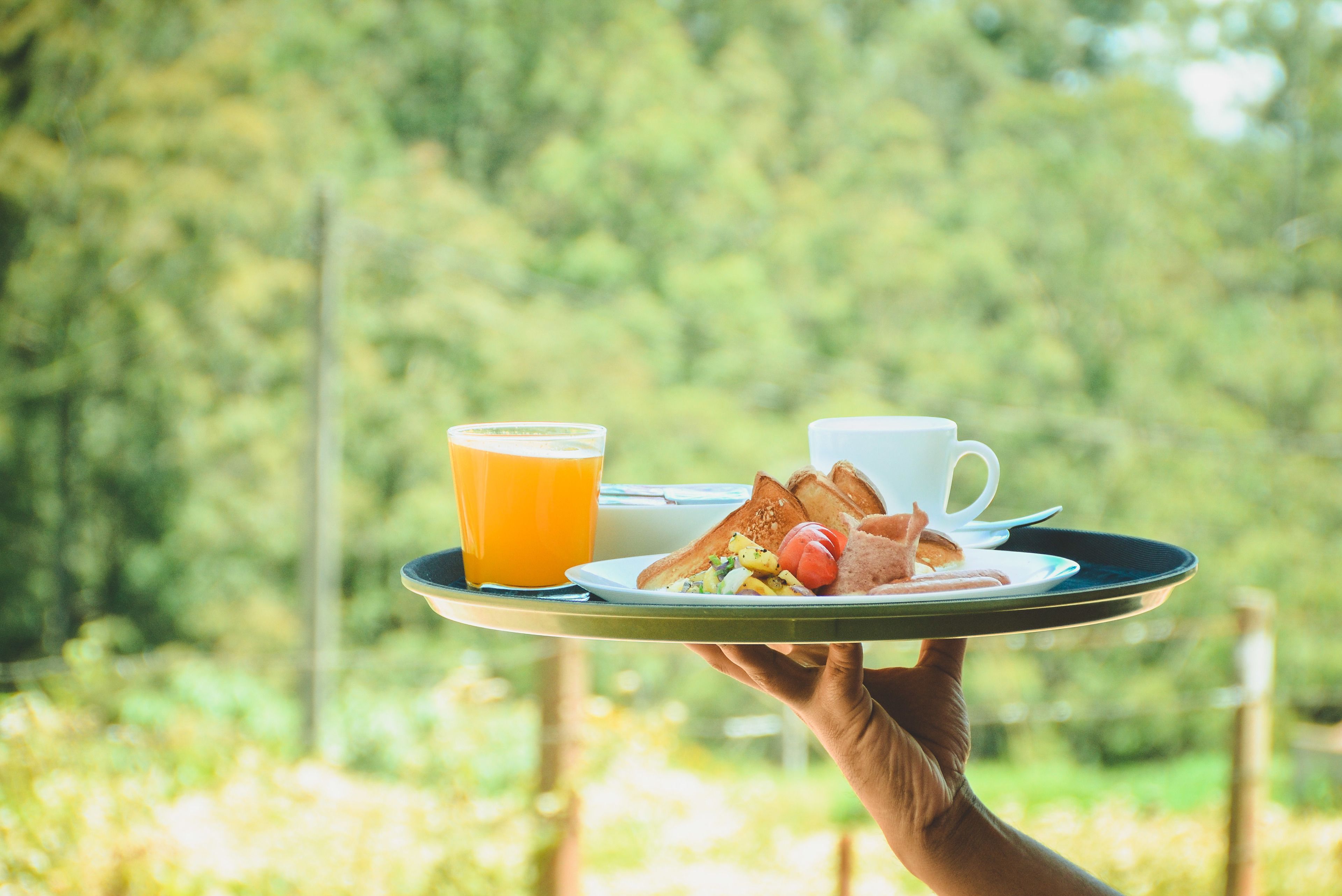 Una bandeja con tostadas, huevos, tomates, una taza de café y un vaso de zumo de naranja.