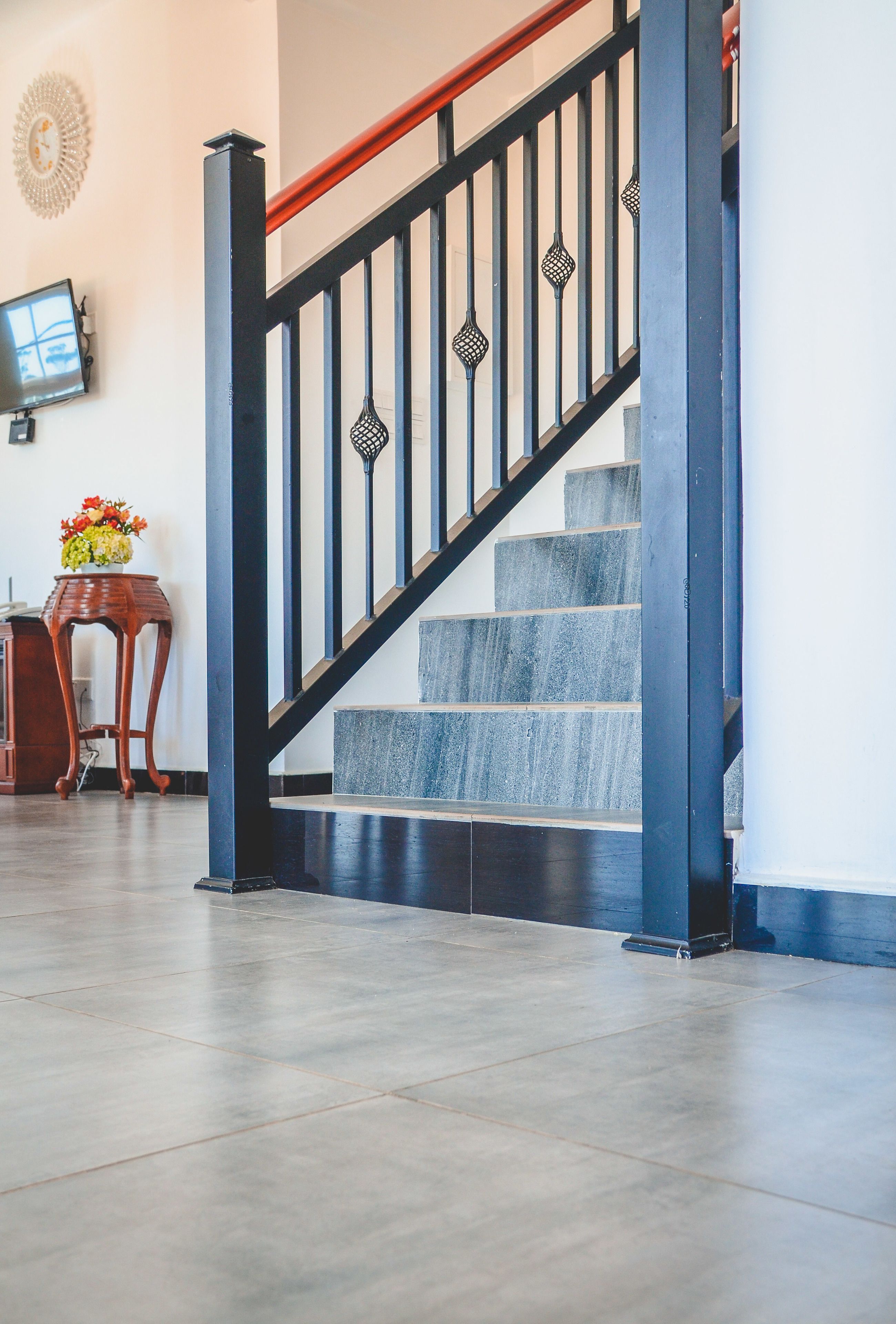 A staircase with black balusters and a wooden handrail, leading to a landing with a flat floor.