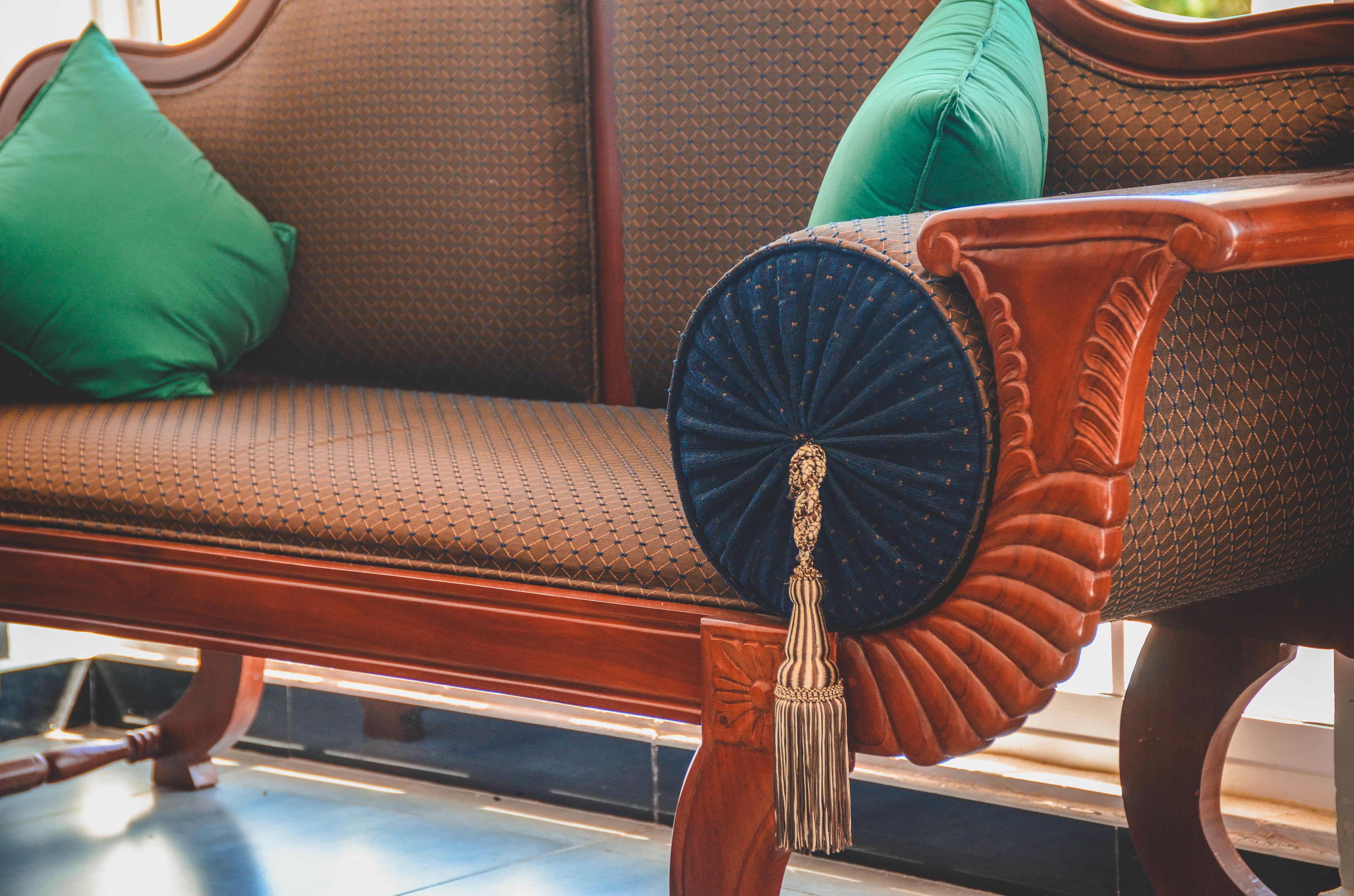 Un banco de madera con respaldo decorativo y cojín verde.