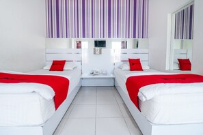 A hotel room with two beds, each with white bedding and red pillows, a white nightstand, and a mirror above the beds. - RedDoorz near Terminal Batu Ampar (Balikpapan)