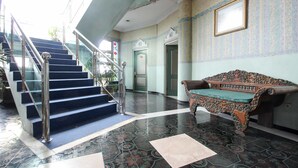 A lobby with a staircase, a bench, and patterned flooring. - Akur Hotel Malioboro (Yogyakarta)