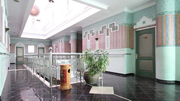 A spacious lobby with a high ceiling, a central plant, a fire extinguisher, and a door with a number sign. - Akur Hotel Malioboro (Yogyakarta)