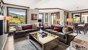 Ein geräumiges Wohnzimmer mit großem Fenster und schöner Aussicht, einem Essbereich mit Tisch und Stühlen sowie einer gemütlichen Sitzecke mit Sofas und Couchtisch.
