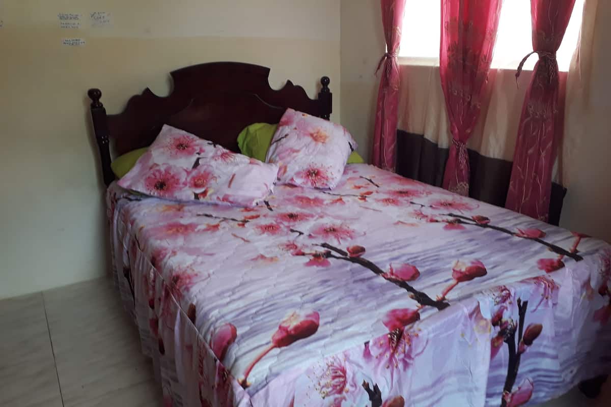 Una cama con una colcha estampada con flores, un cabecero de madera y un cojín verde.