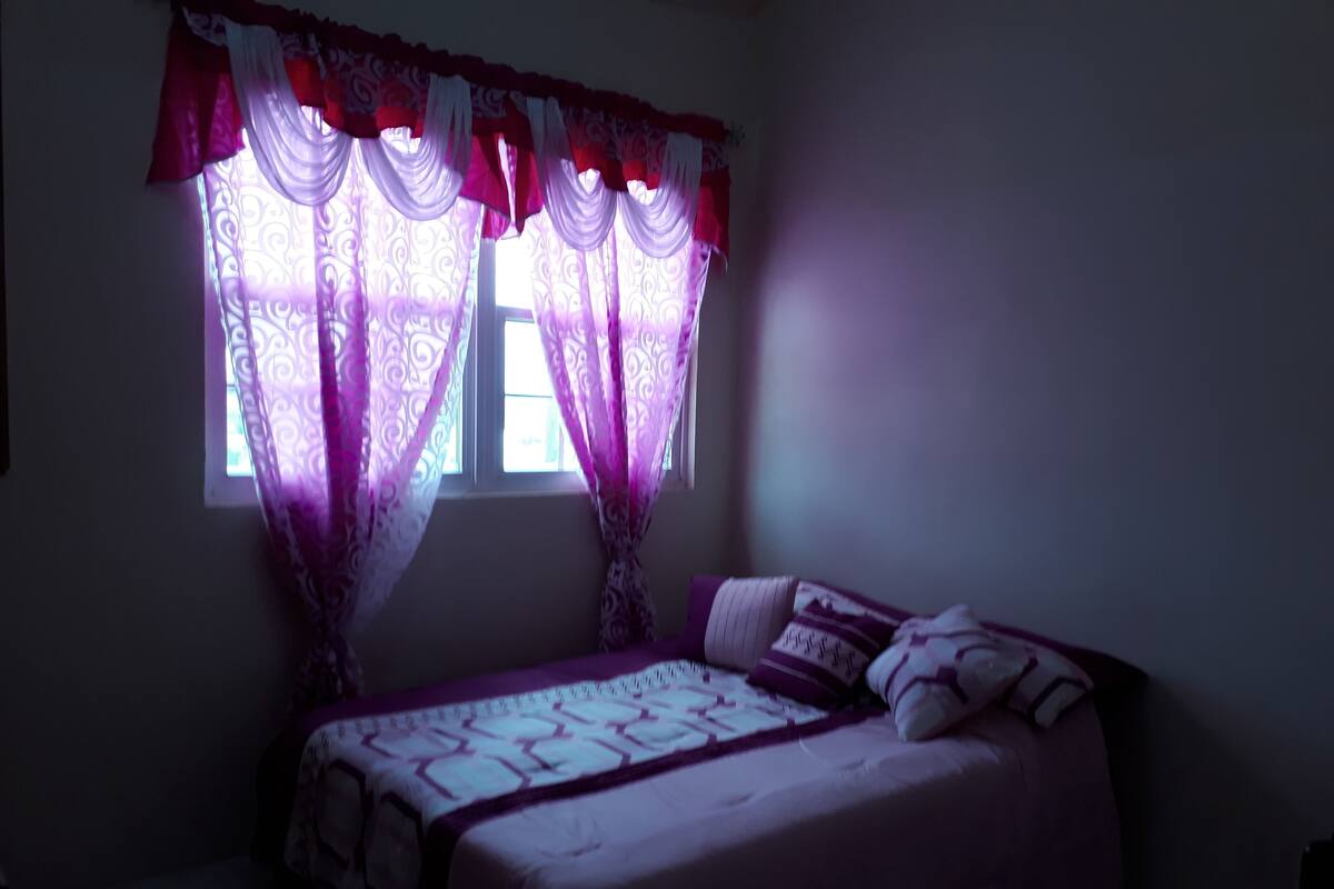 Un dormitorio con cama, cortinas y ventana.