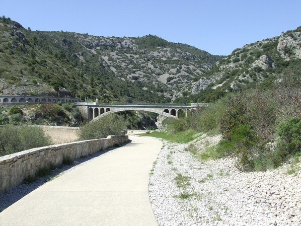 Un puente de piedra sobre un río, rodeado de colinas rocosas y vegetación escasa.