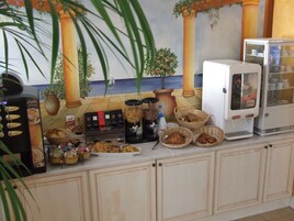 Una encimera de cocina con una cafetera, un refrigerador y diversos alimentos.