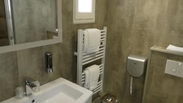 Une salle de bain avec un lavabo blanc, un miroir, un porte-serviettes et des toilettes.
