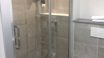 Un baño moderno con ducha de vidrio, inodoro y lavamanos.