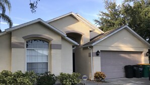 A single-story house with a garage, a large window, and a well-maintained lawn. - 4BR 3BA Home in Rolling Hiils by CV-7901 (Kissimmee)