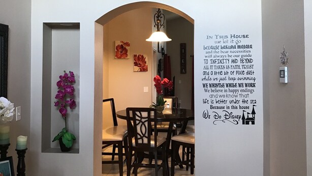 A dining area with a table and chairs, a decorative orchid plant, and a wall with a motivational quote. - 4BR 3BA Home in Rolling Hiils by CV-7901 (Kissimmee)