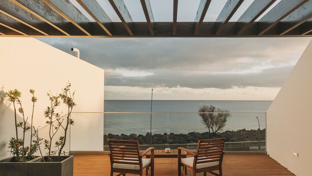 A wooden deck with a table and chairs overlooking the sea. - Ocean Views by Azores Villas (Ponta Delgada)