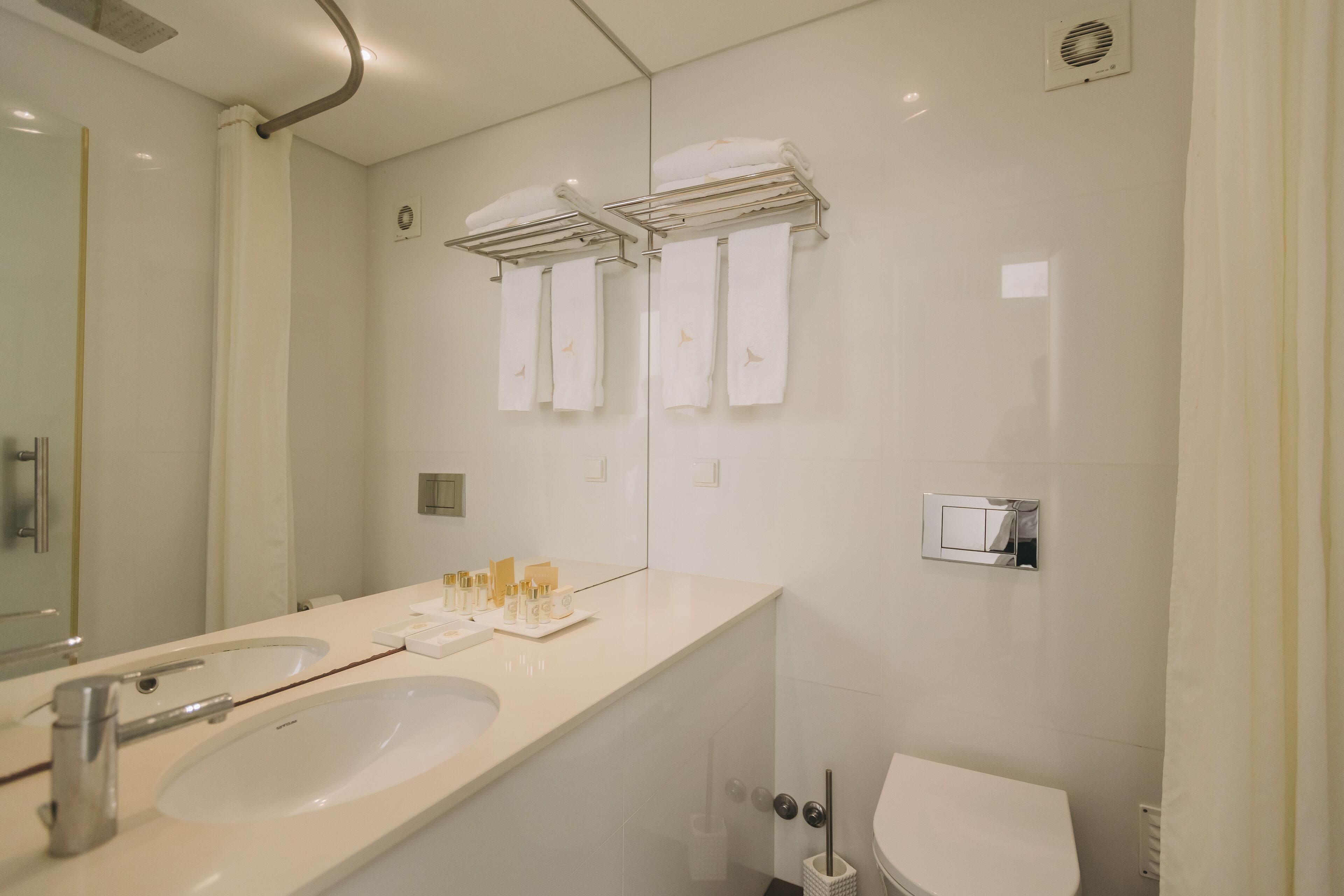 Ein modernes Badezimmer mit zwei Waschbecken, einer Toilette und einem Handtuchhalter.