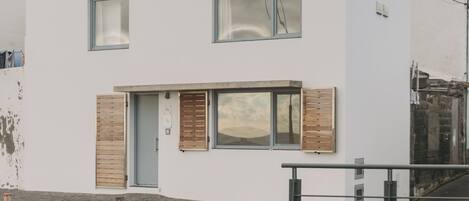 Un edificio moderno a due piani con ampie finestre, tetto piano e un piccolo portico.