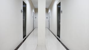 Un pasillo con paredes blancas y un piso de baldosas brillantes, que conduce a puertas a ambos lados.