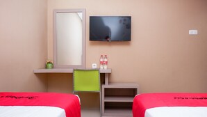 Habitación de hotel con dos camas, televisión, escritorio con silla y estante con espejo y dos botellas.