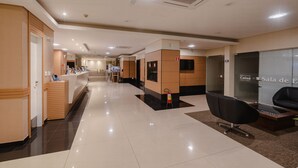 Un vestíbulo de hotel con mostrador de recepción, zona de estar y una escalera que conduce a los pisos superiores.