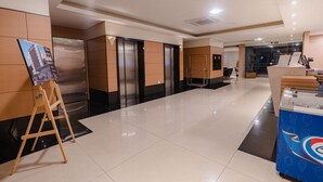 Un moderno vestíbulo de hotel con ascensores, una recepción y una zona de restauración.