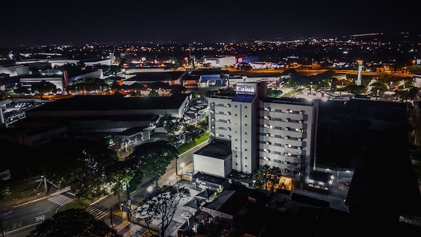 Un hotel con varios pisos, un estacionamiento y vistas de la ciudad iluminada por la noche.
