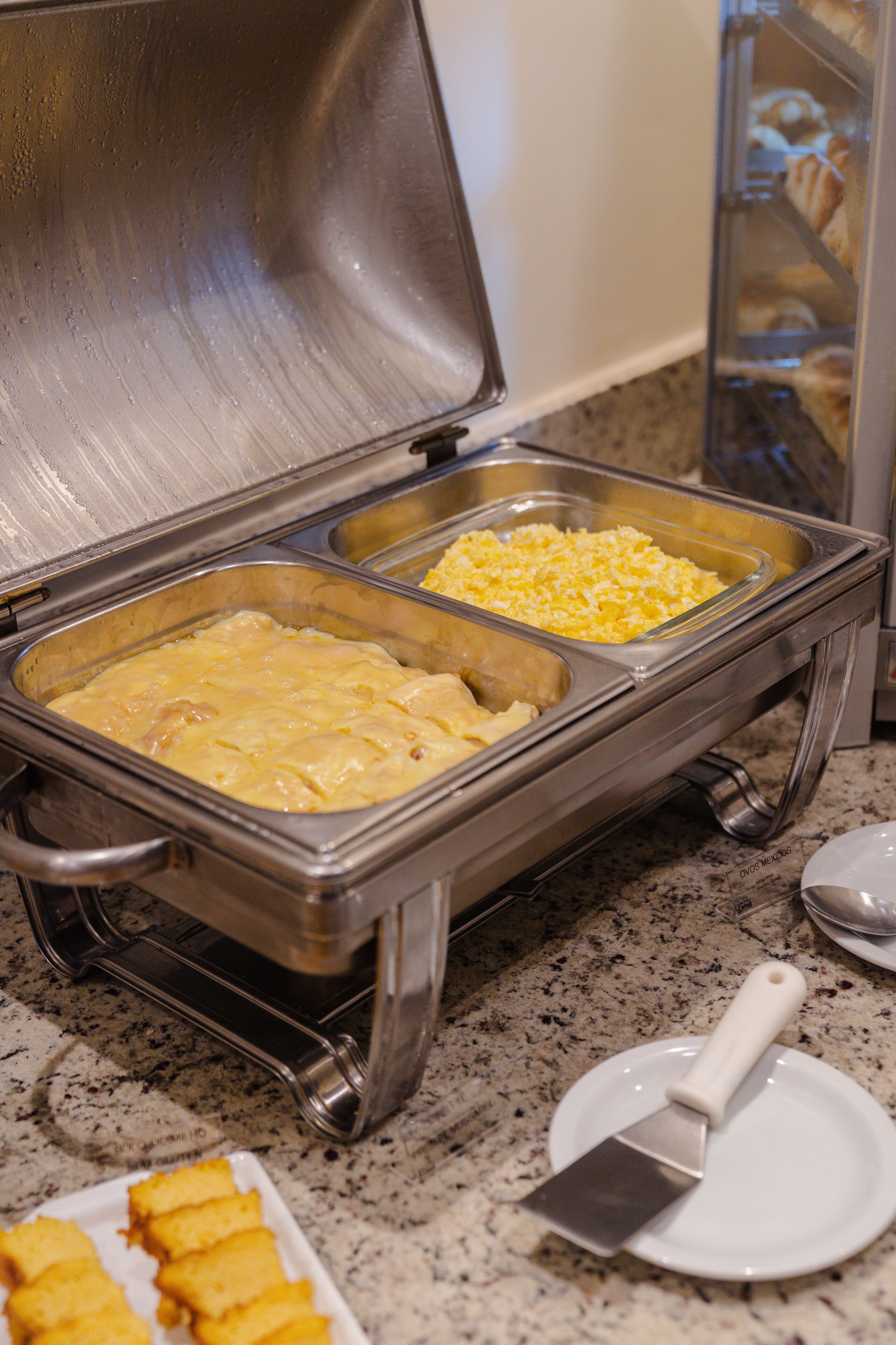 Un buffet avec deux plateaux de service : l’un contient un plat crémeux et l’autre, du fromage râpé.