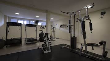 Uma academia com diversos equipamentos de exercício, incluindo esteiras, máquinas de peso e pesos livres.