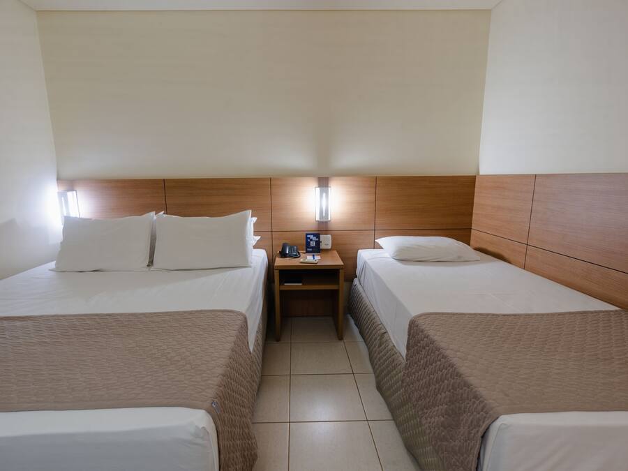 Een hotelkamer met twee bedden, een nachtkastje en een wandlamp.