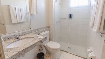 Un bagno con lavabo su piano in granito, WC bianco e cabina doccia in vetro.