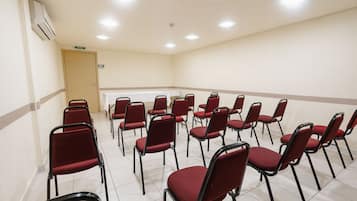 A conference room with rows of red chairs and a door labeled "BAILA".