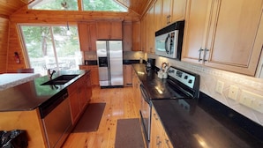 Una cocina moderna con armarios de madera, electrodomésticos de acero inoxidable y un amplio ventanal que proporciona luz natural.