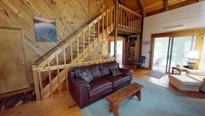 Un interior de madera con un sofá de cuero, un banco de madera y una escalera.