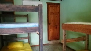 Une chambre de dortoir avec des lits superposés et une porte en bois.