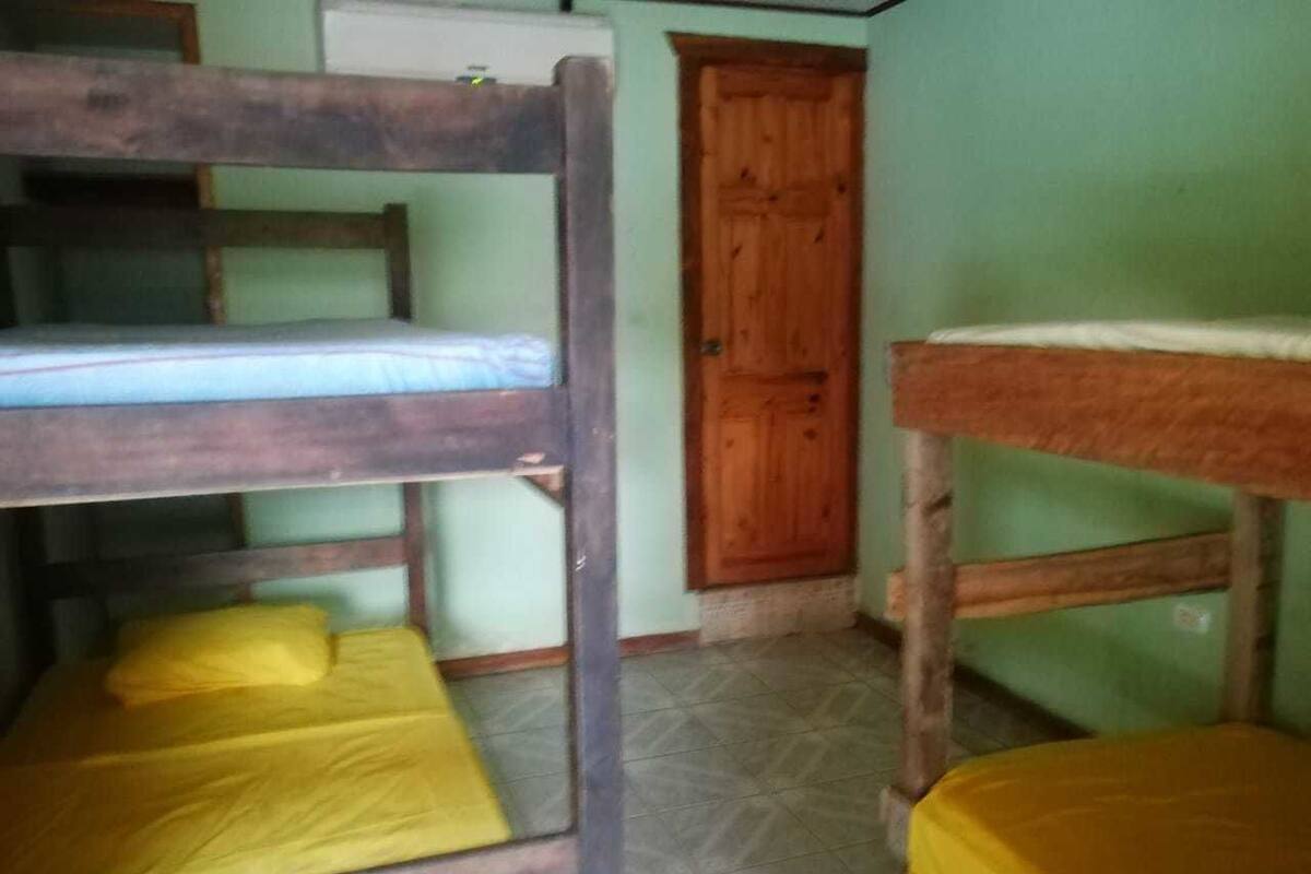 A dormitory room with bunk beds and a wooden door.
