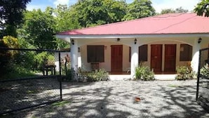 Une maison avec un toit rouge, des murs blancs et des portes en bois.