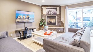 A modern living room with a flat-screen TV, a fireplace, a sofa, and a coffee table. - Waking up in your own 3BR beach home!-C8 (Newport Beach)
