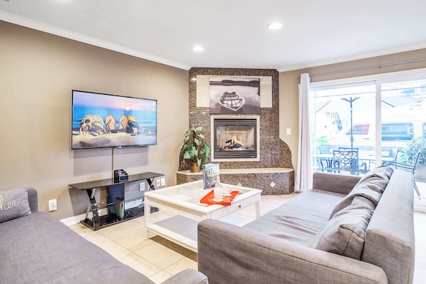 A modern living room with a flat-screen TV, a fireplace, a sofa, and a coffee table.