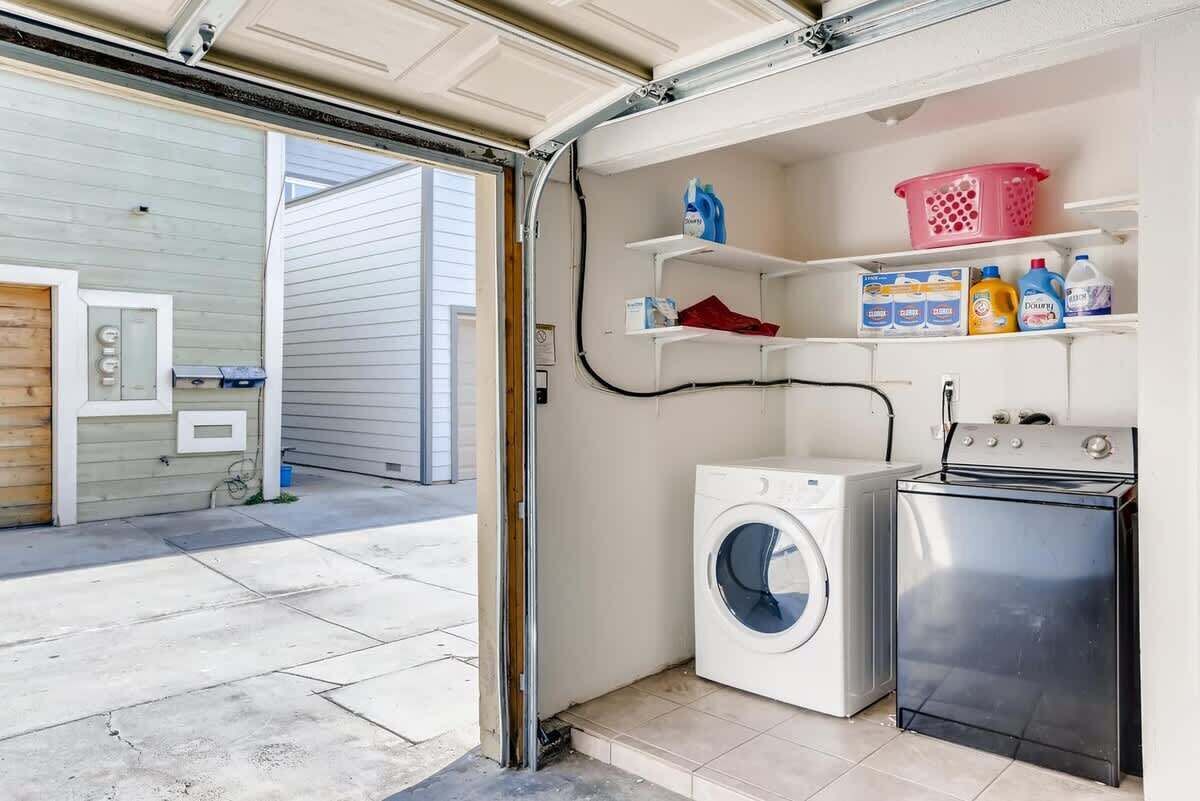 A laundry room with a washing machine, dryer, shelves with laundry supplies, and a utility room with a water heater.