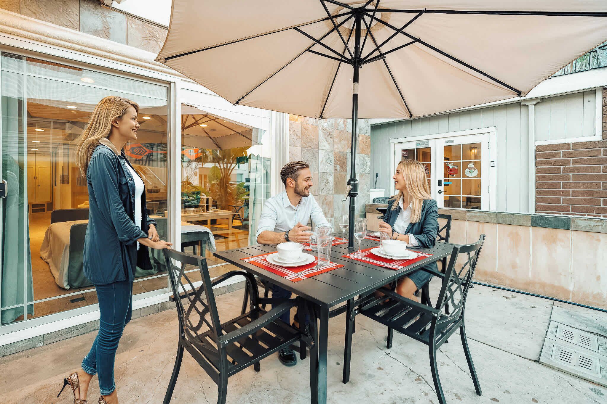 Een terras met een tafel voor vier personen, omringd door stoelen, en een grote parasol die schaduw biedt.