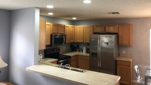 A kitchen with wooden cabinets, stainless steel appliances, and a light gray wall.
